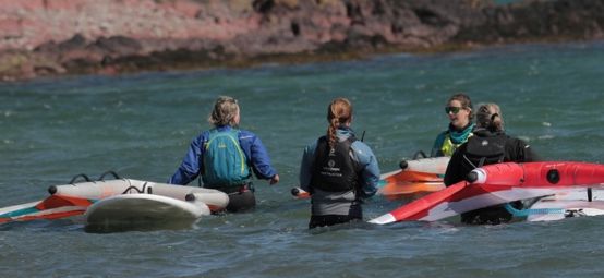 RYACW Chair Sian Reynolds in the sea with three other people while learning winging during the Big Day Out 2024, Dale in Pembrokeshire.