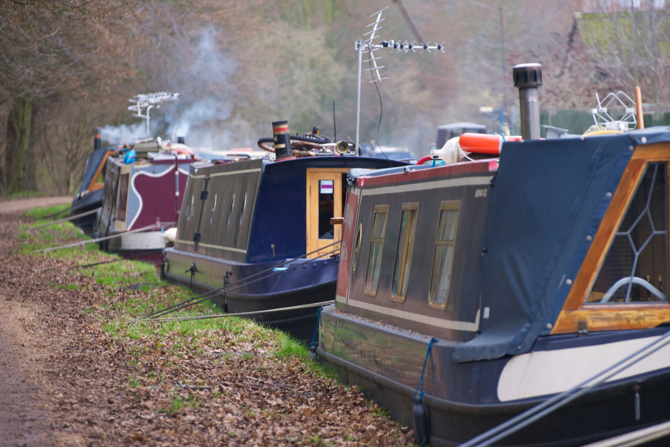 canal boats moored along a river
