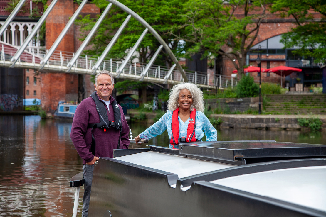 Long shot of two sailors on canal boat smiling