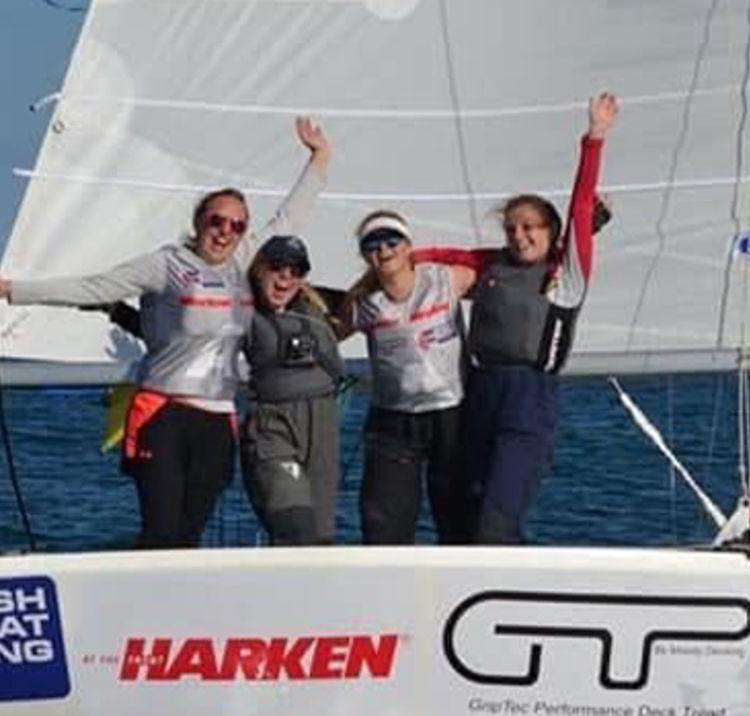 Three people on a boat smiling and laughing at the camera