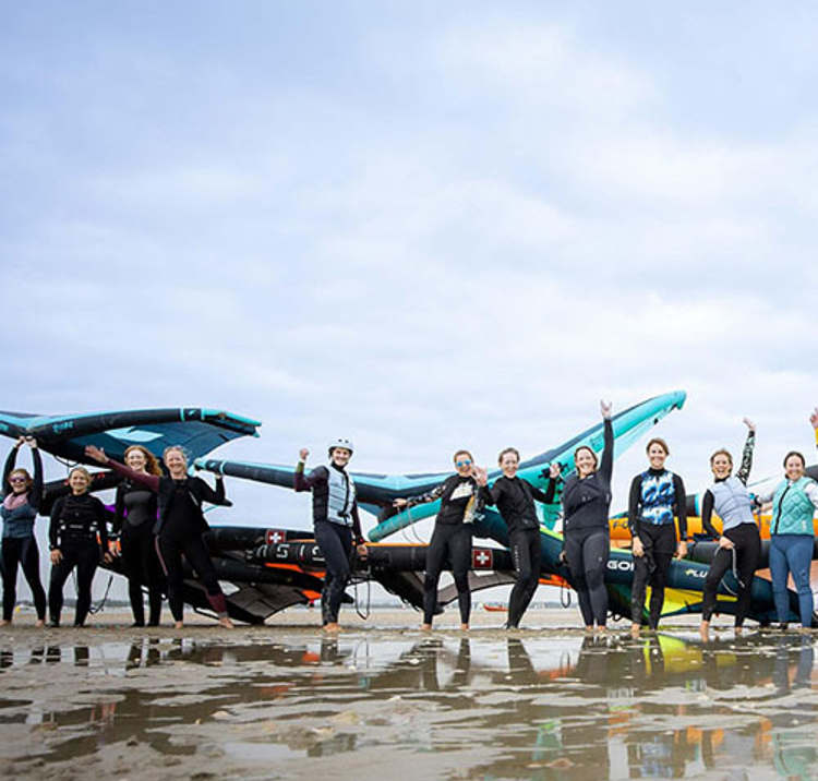a group of wing surfing women cheering on a beach