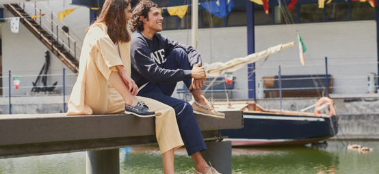 Man and women sitting on the deck, smiling in Sebago shoes
