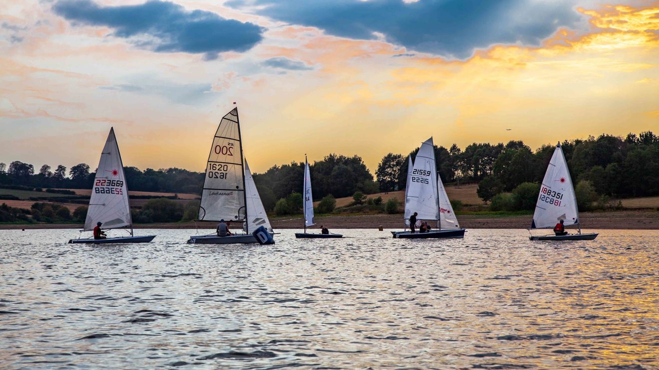 Long shot of boats on water with sunset