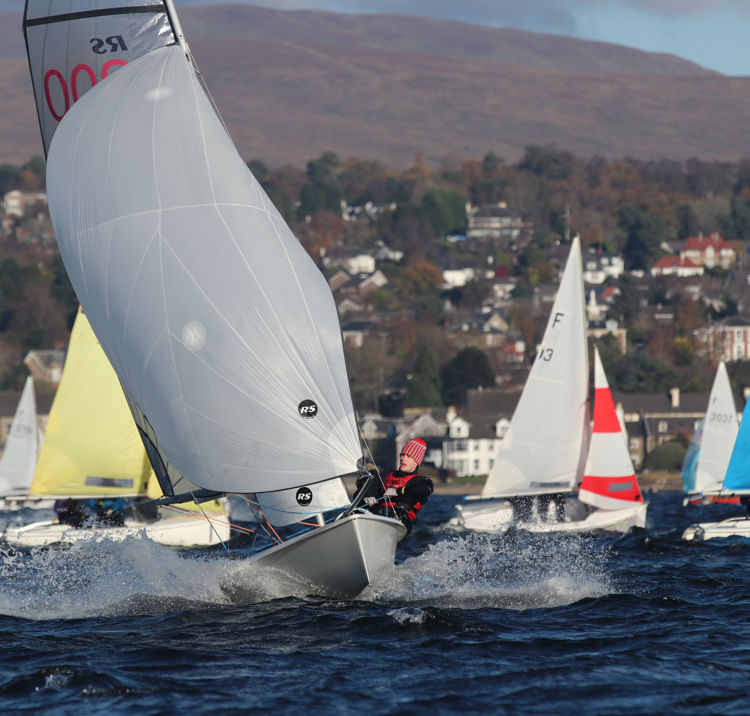 Long shot of sailboats with town and fields in the background