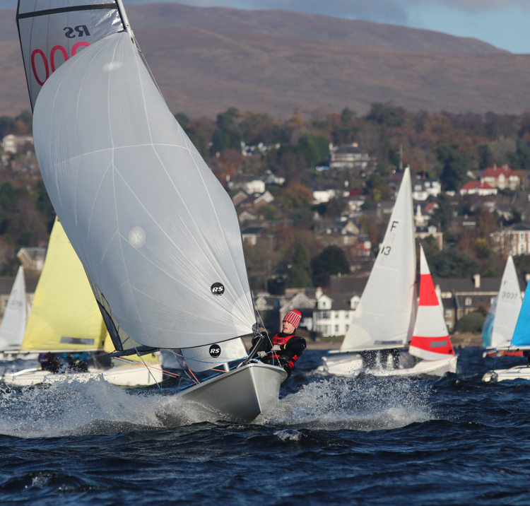 Long shot of sailboats with town and fields in the background
