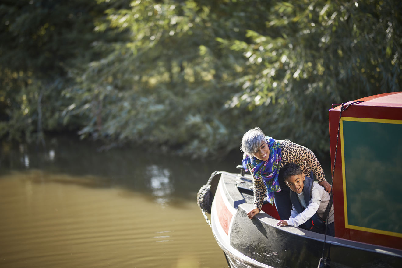 mother and son leaning over the side of a canal boat looking happy