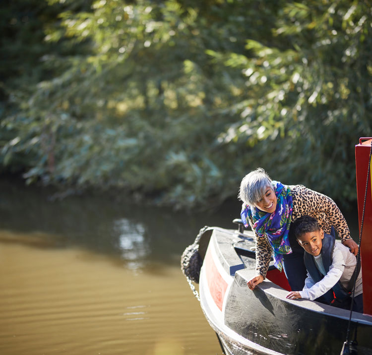 mother and son leaning over the side of a canal boat looking happy