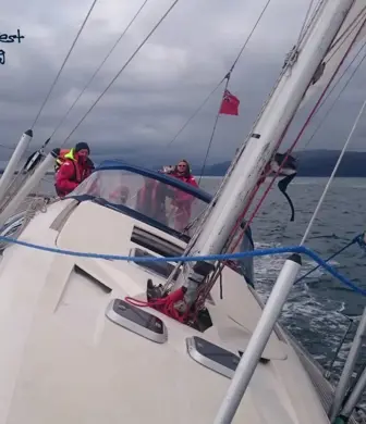 Two people receiving training from Go West Sailing on a yacht that is at a 45 degree angle to the water