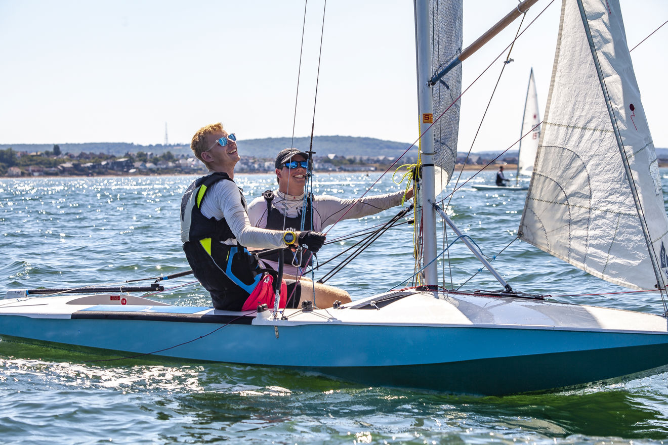 Two dinghy sailors smiling in sparkling blue waters