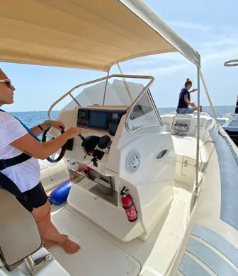 A lady driving a large rigid inflatable boat (RIB) from Barcelona Watersports approaching a cardinal marker