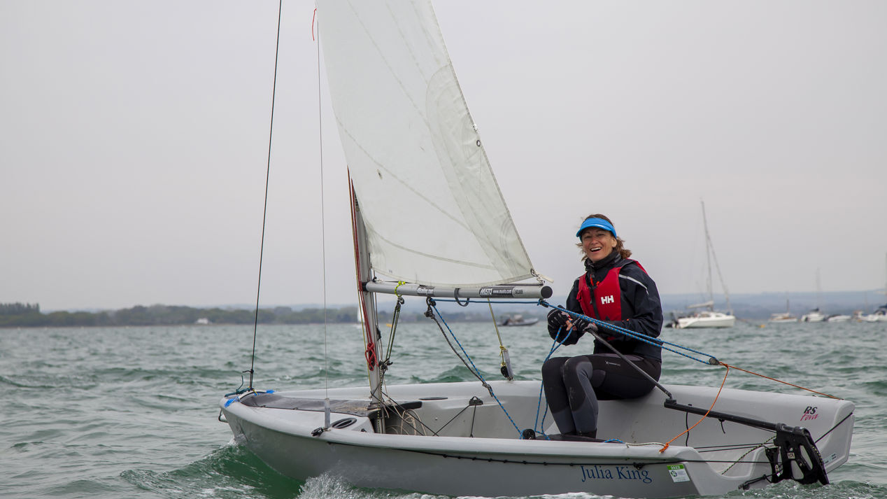 wide shot of a woman steering an RS feva sailing dinghy