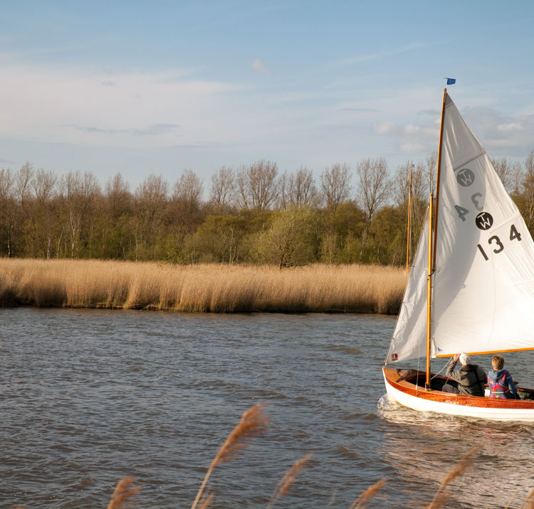Lone dinghy sailing through lake