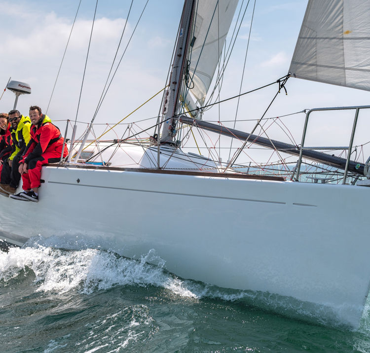 Sail cruising crew hanging off the side of their boat
