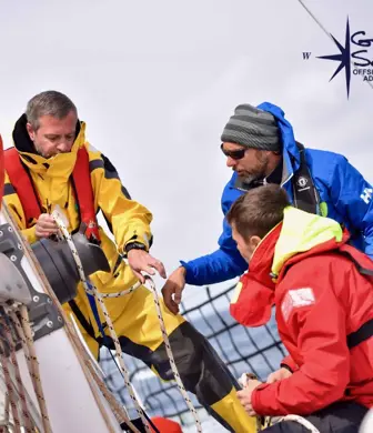 Two students watching an instructor demonstrate sailing techniques on a yacht with Go West Sailing
