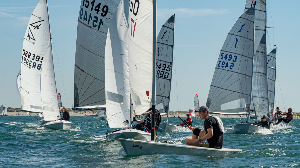 Dinghies racing across blue water during multi class