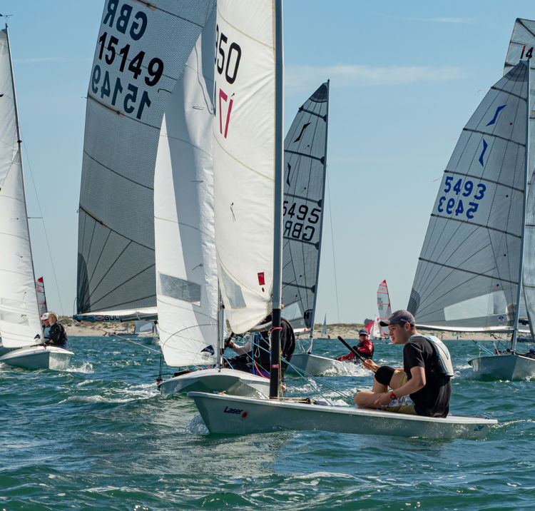 Dinghies racing across blue water during multi class