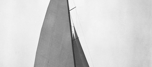 Black and white image of a single sailing boat travelling through the water