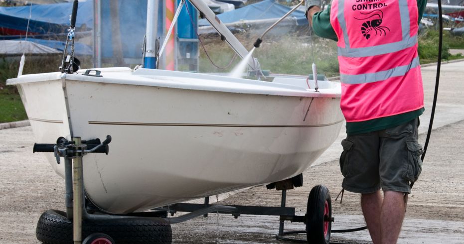 man hosing his dinghy whilst on shore on wheels
