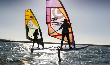 silhouettes of windsurfers at sunset