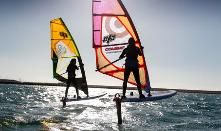 silhouettes of windsurfers at sunset