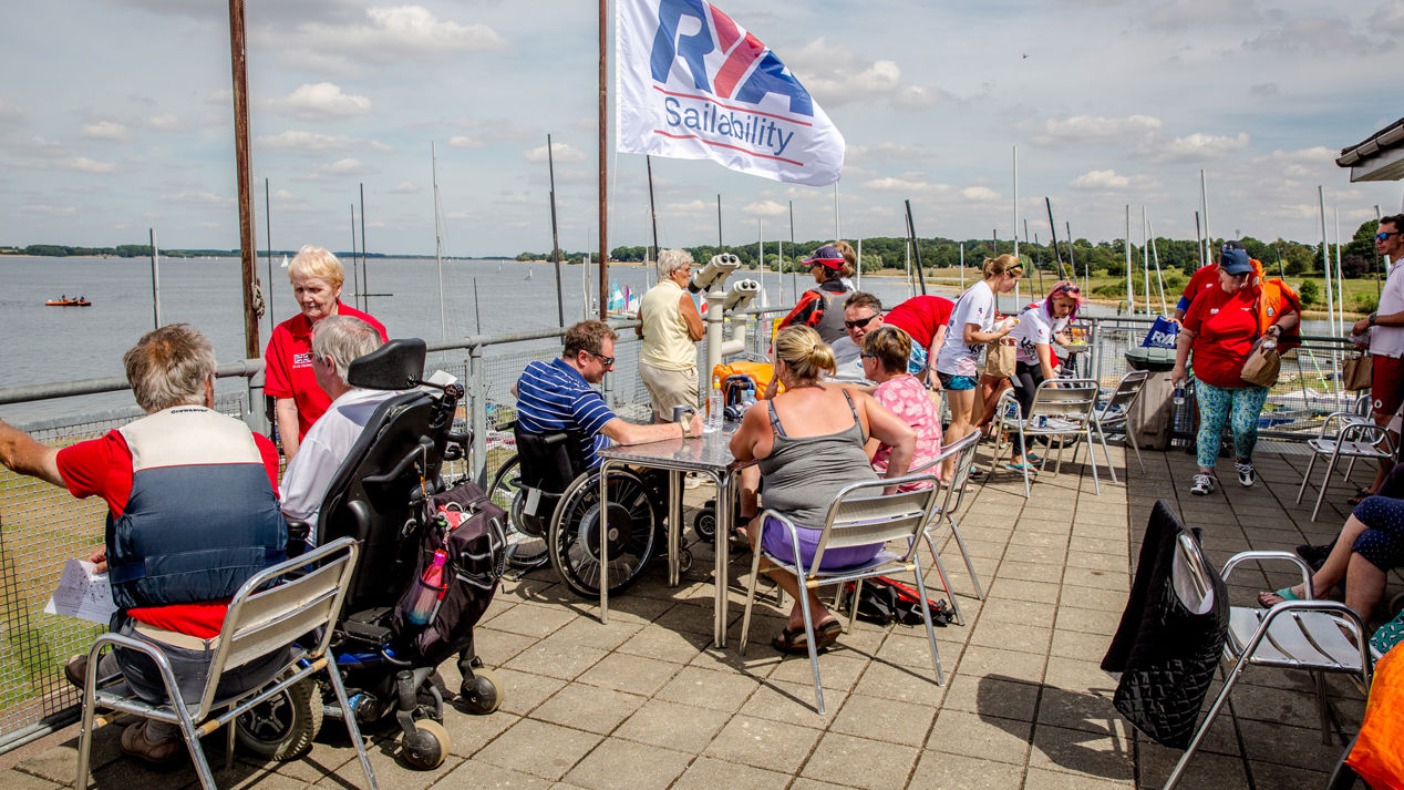 People sat at tables outside, enjoying a sailability event 