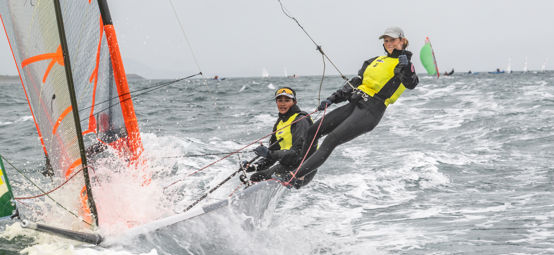 Long shot of two sailors steering a dinghy