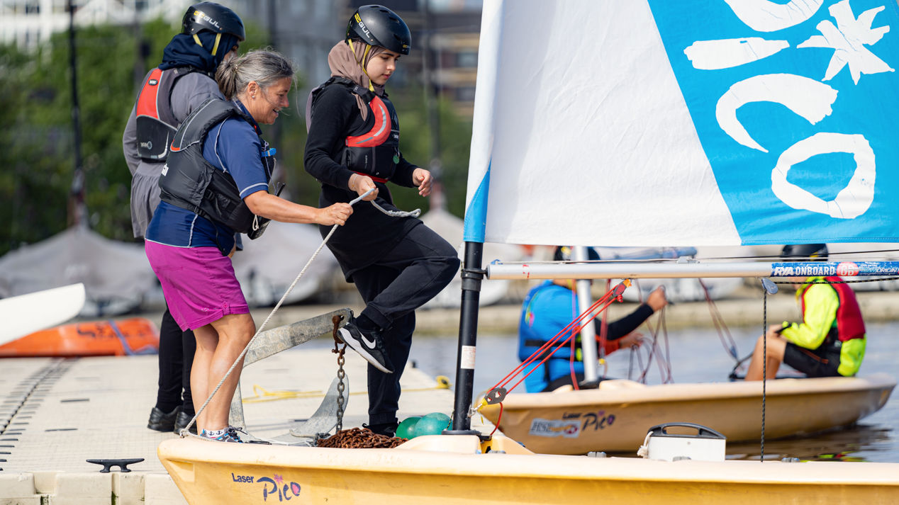 young girl stepping in to a pico, whilst women is holding it with her foot