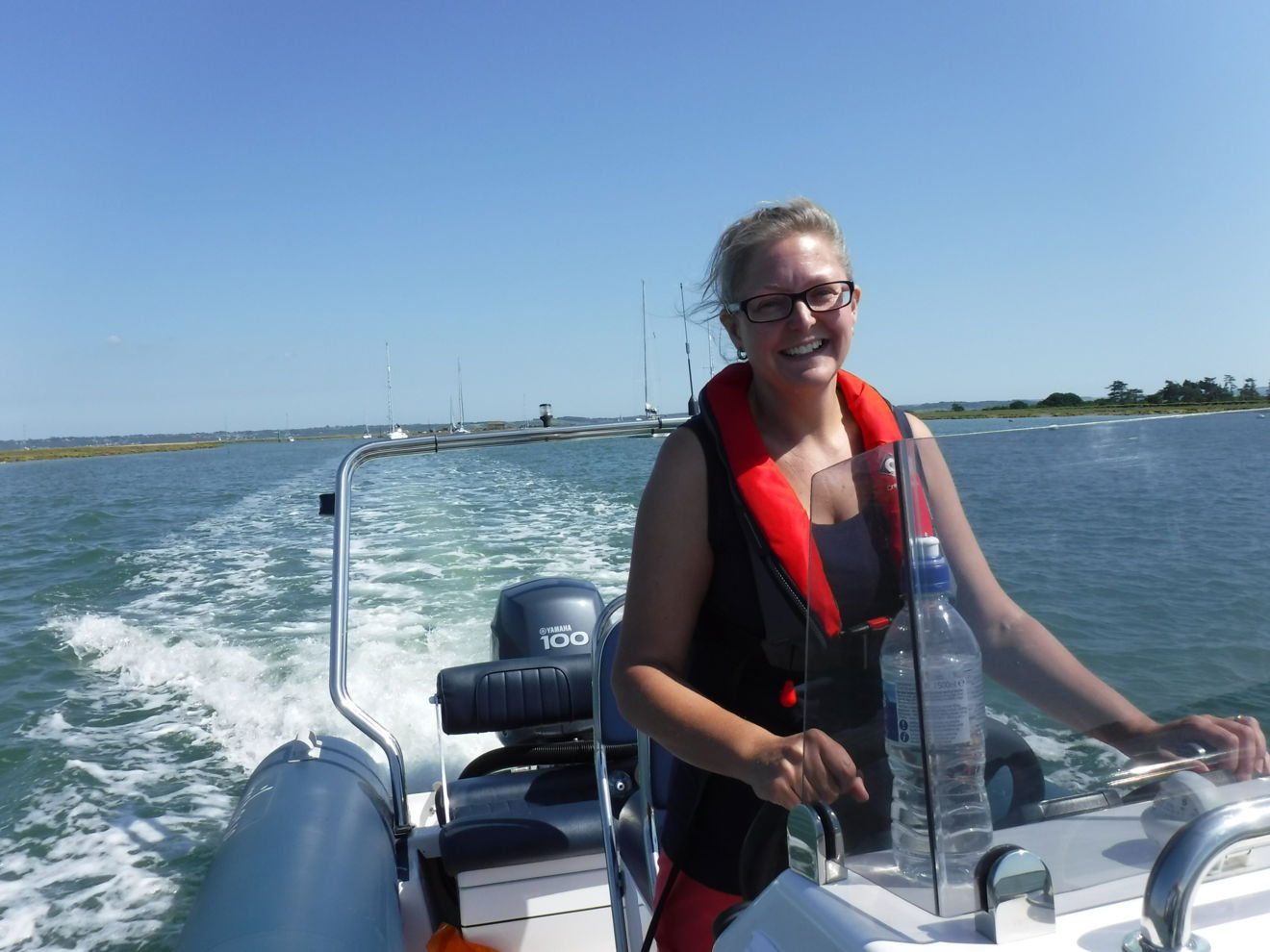 Victoria Jacobs steering a powerboat on the ocean, smiling.