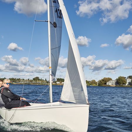 two people sat on one side of a dinghy whilst sailing across the ocean