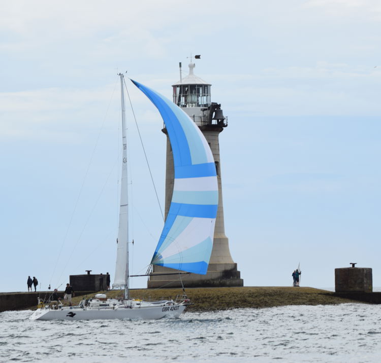 Two handed boat sailing past a lighthouse 