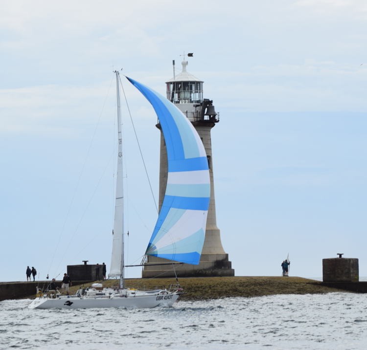 Two handed boat sailing past a lighthouse