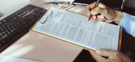 clipboard with paperwork on, and someone about to sign 