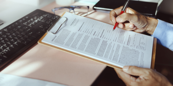 clipboard with paperwork on, and someone about to sign 