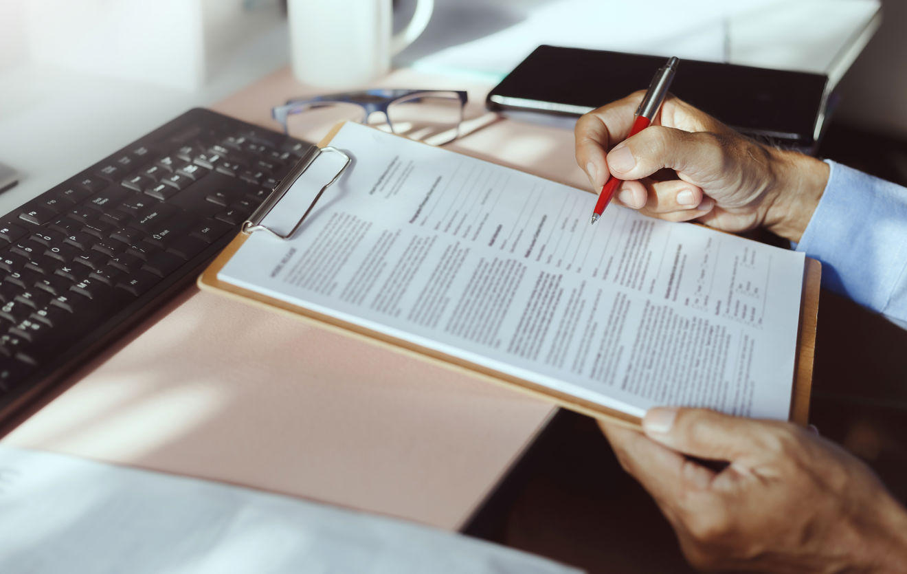 clipboard with paperwork on, and someone about to sign 