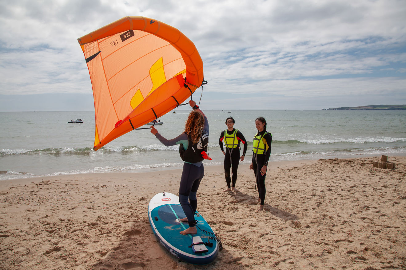 Instructor demonstrating how to use a wing and board on beach