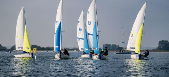 Long shot of Eric Twiname racing dinghies on water