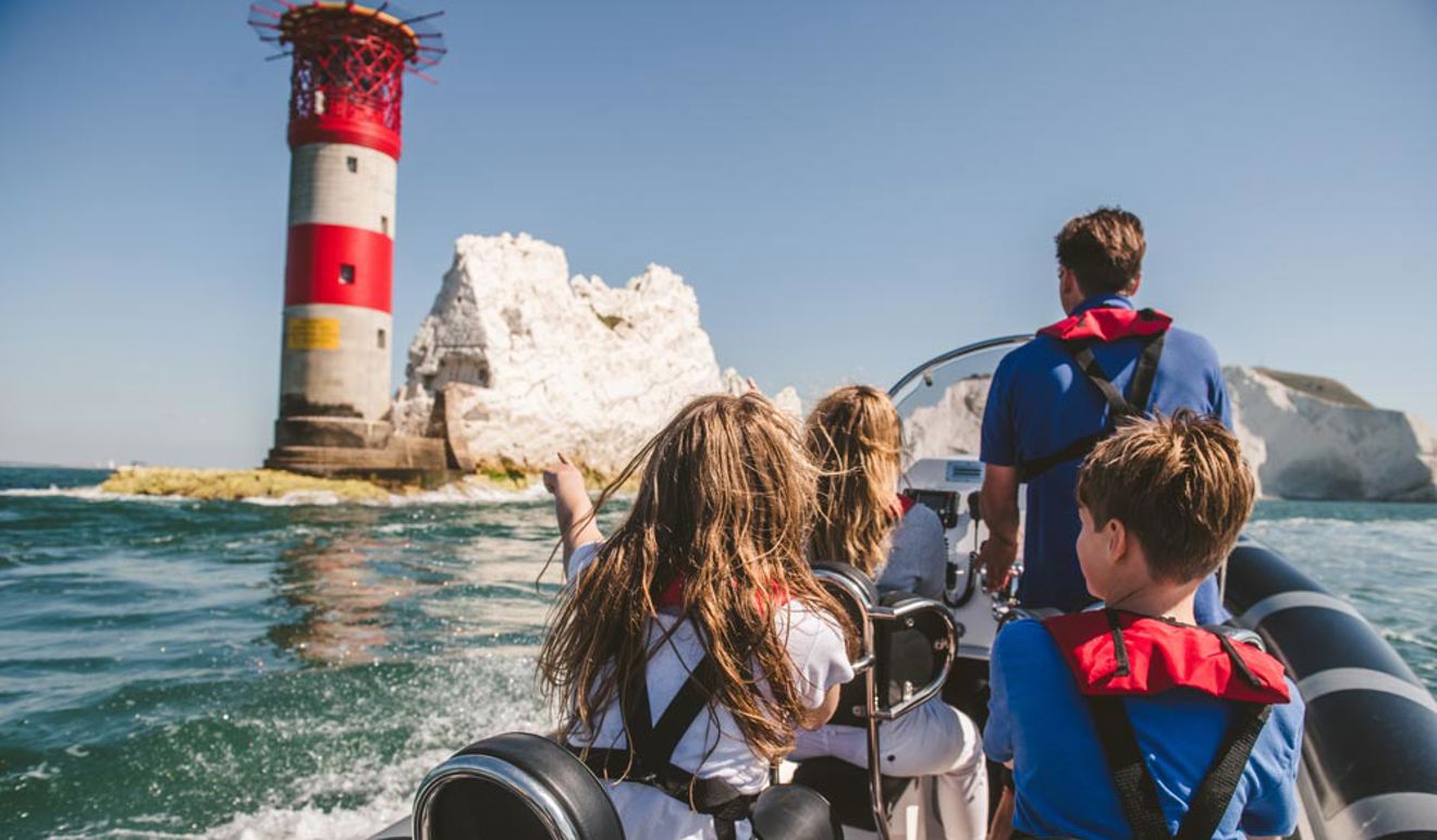 family on a powerboat heading towards a lighthouse