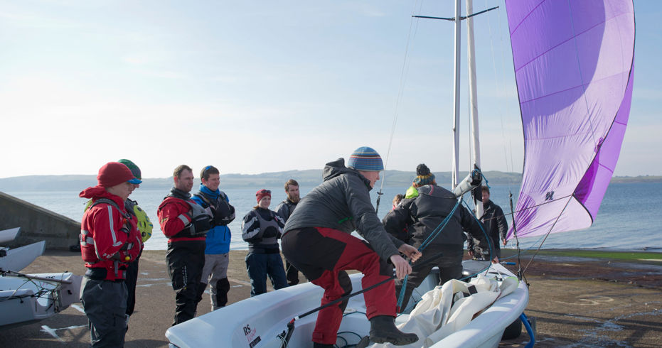 A volunteer on a dinghy showing a group how to use it