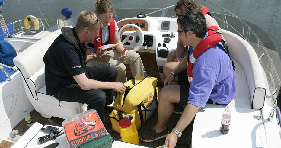 4 people sitting on a boat going through the safety equipment