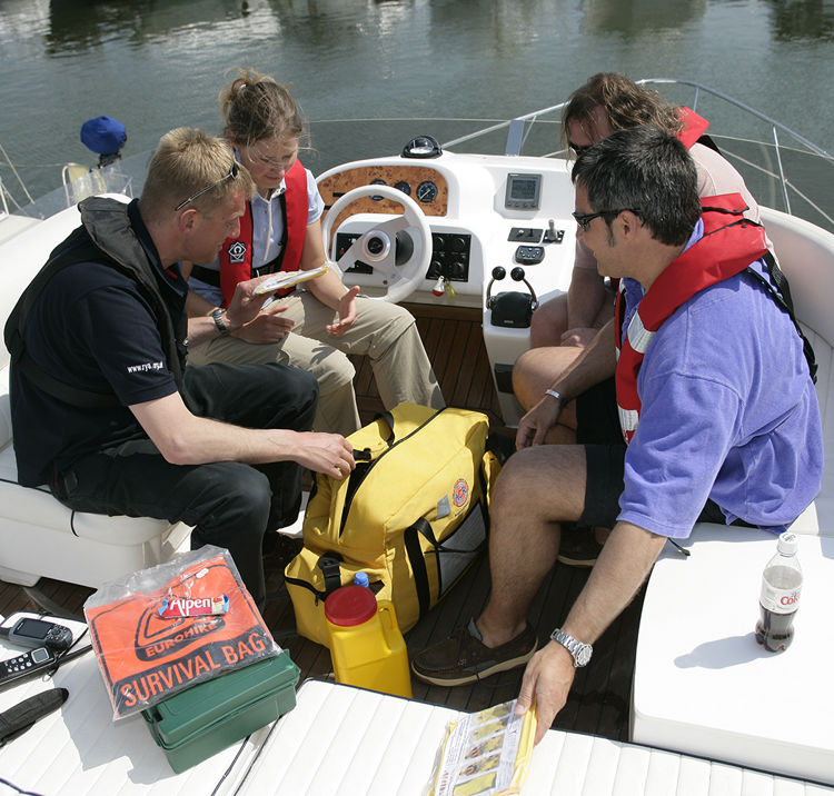 4 people sitting on a boat going through the safety equipment