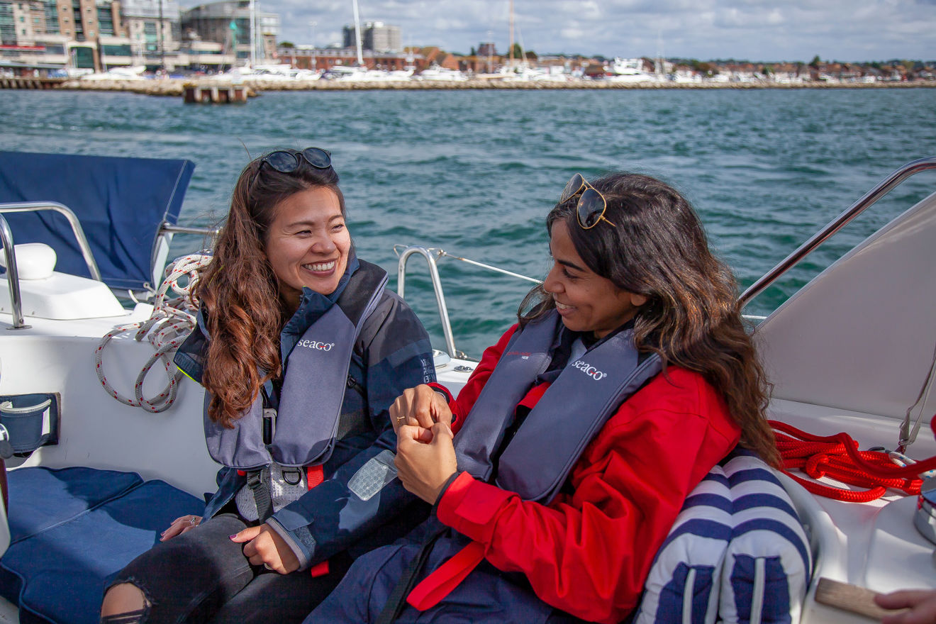 two women sitting on a large yacht smiling at each other