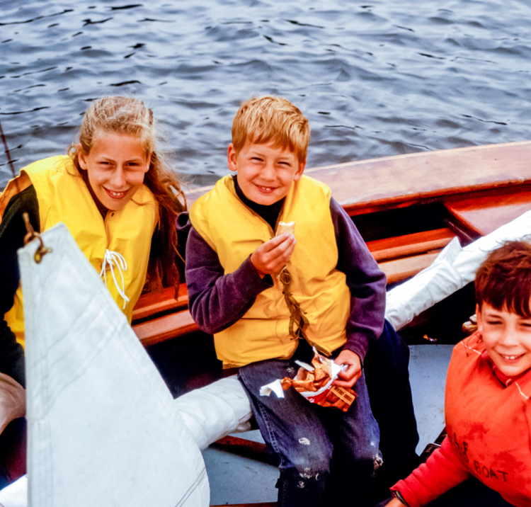 Children laughing and smiling on a small dinghy