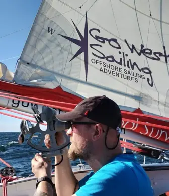 A man on a Go West Sailing yacht demonstrating astronavigation equipment