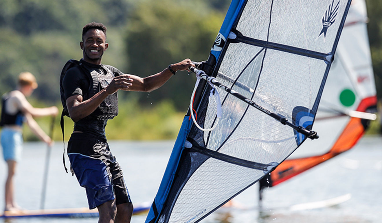 man windsurfing on lake and smiling