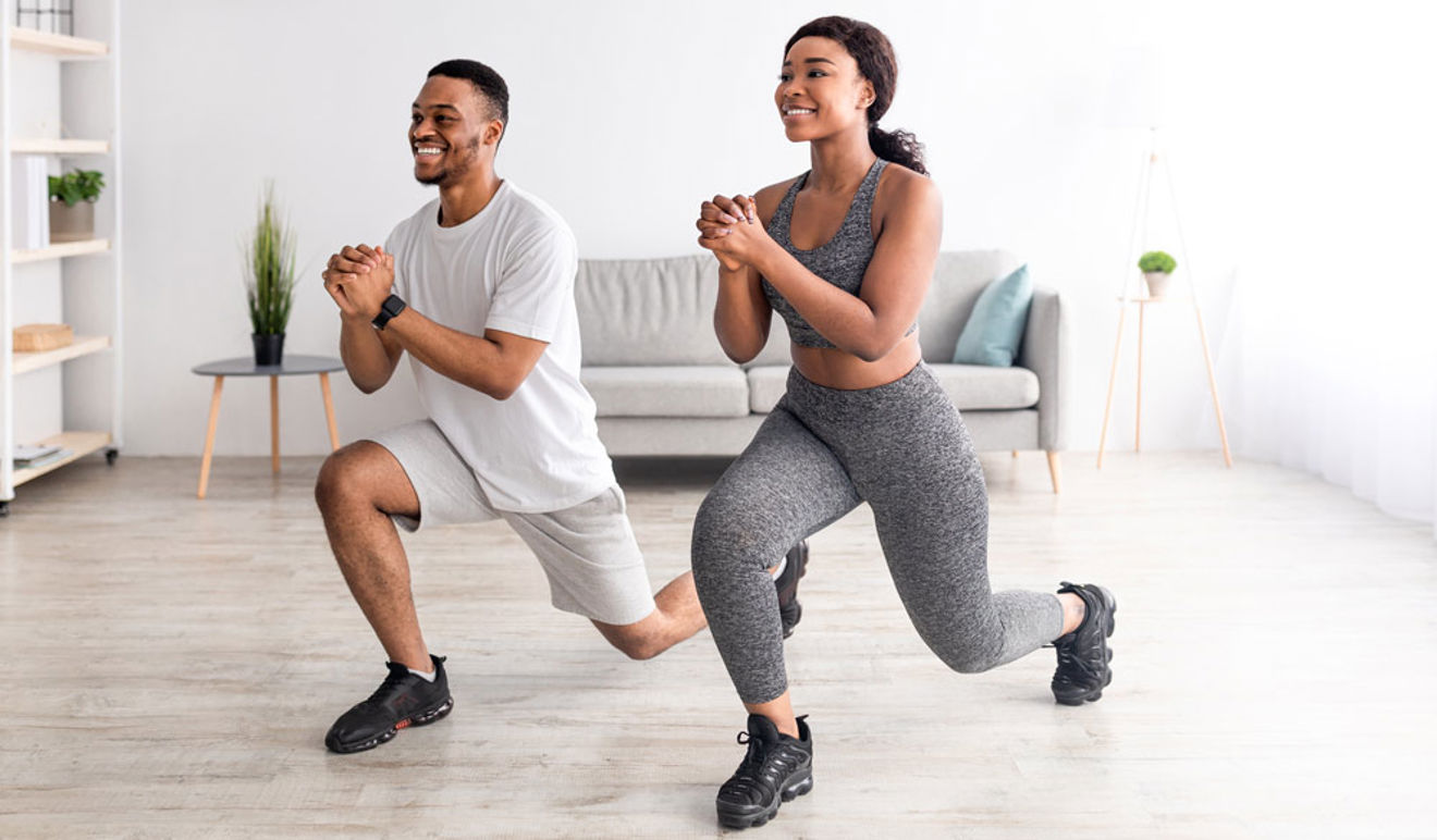 An image of a man and woman in a room performing the exercise Reverse lunge