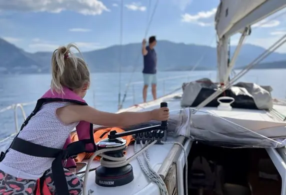 A young girl sailing on a yacht promoting family sailing courses at Aegean Sailing School, Aegina, Greece