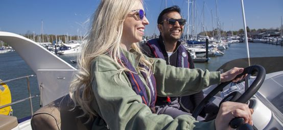 A man and a woman are sitting at the helm of a boat.