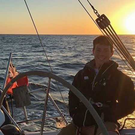 sailor steering boat at sunset