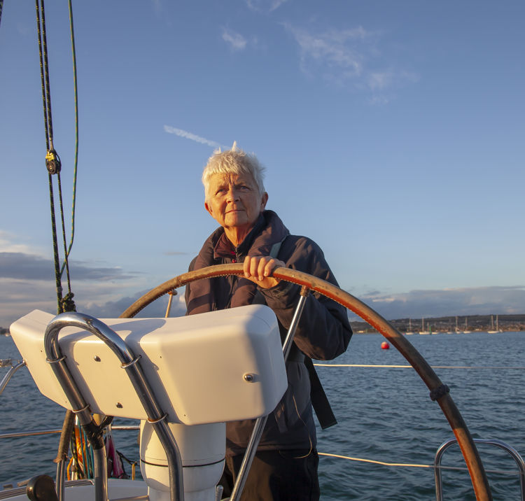 woman steering boat at sunset