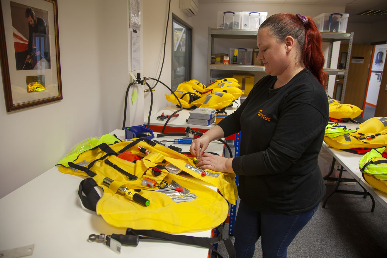 A woman inspecting several life jackets